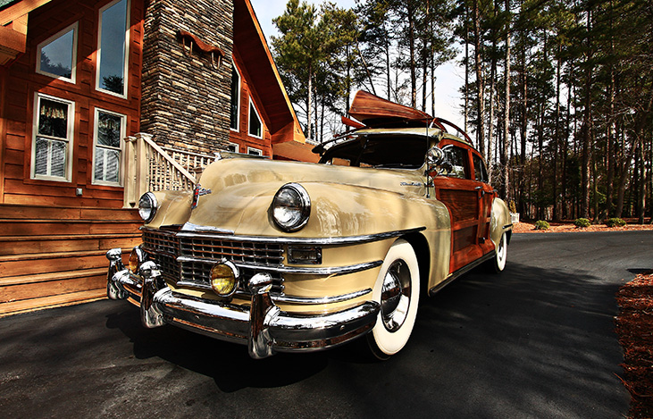 Photograph of vintage car in front of lake house